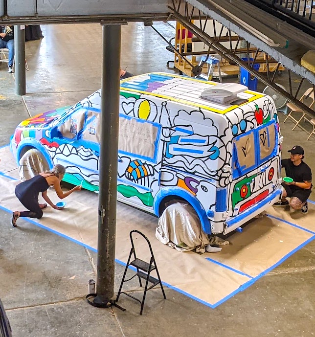 A cargo van having colorful art painted on it by several people